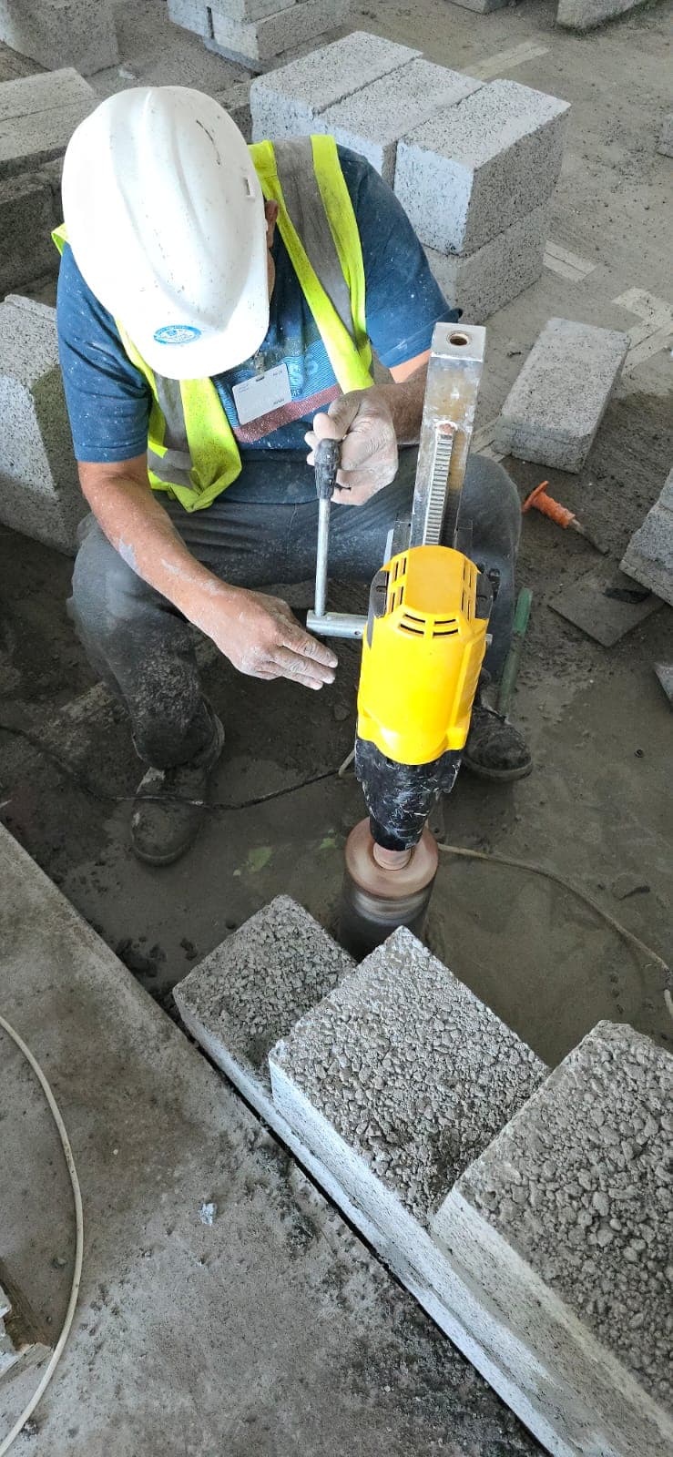 Core cutting service UAE - technician operating diamond core drilling machine on concrete Dubai